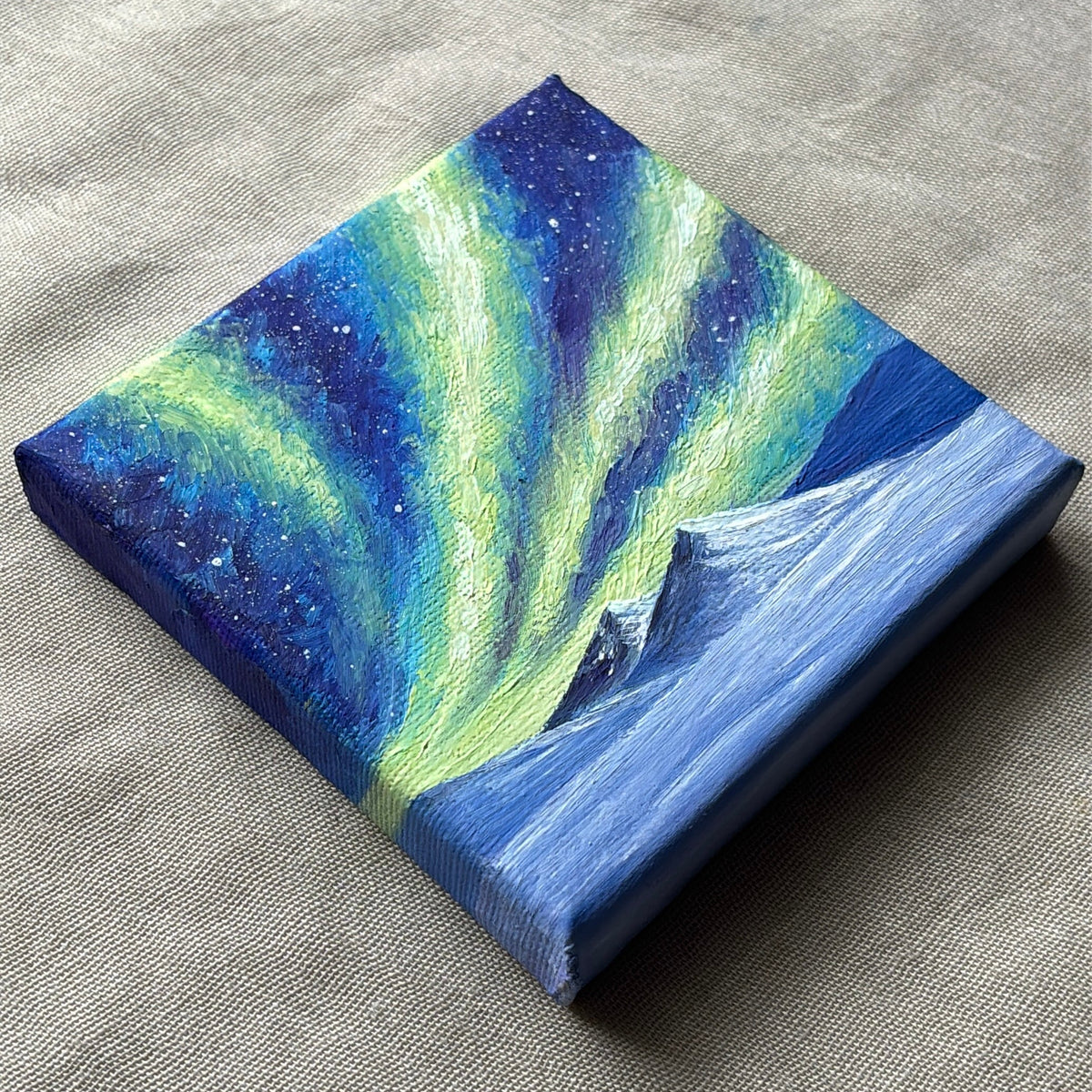 Side view of the northern-lights miniature oil painting showing its painted edges.